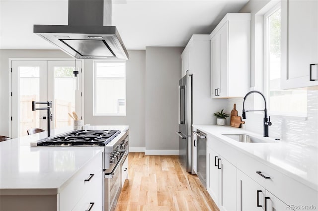 1543 Glencoe St, Denver, CO 80220 - kitchen with wall chimney exhaust hood, a sink, premium appliances, baseboards, and light wood-style flooring