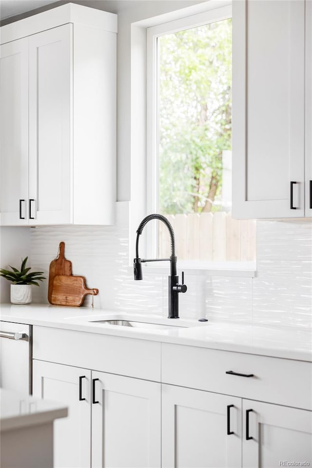 1543 Glencoe St, Denver, CO 80220 - kitchen featuring tasteful backsplash, white cabinets, light countertops, and a sink