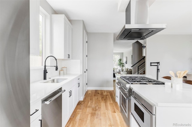 1543 Glencoe St, Denver, CO 80220 - kitchen featuring stainless steel appliances, a sink, island exhaust hood, light wood-style floors, and light countertops