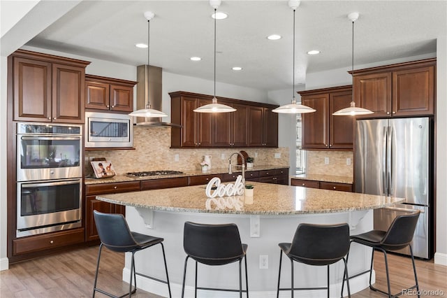 6877 Northstar Ct, Castle Rock, CO 80108 - kitchen with appliances with stainless steel finishes, light wood-type flooring, an island with sink, a kitchen breakfast bar, and recessed lighting