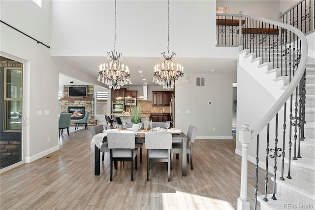 6877 Northstar Ct, Castle Rock, CO 80108 - dining space featuring a fireplace, stairway, a high ceiling, light wood finished floors, and a chandelier