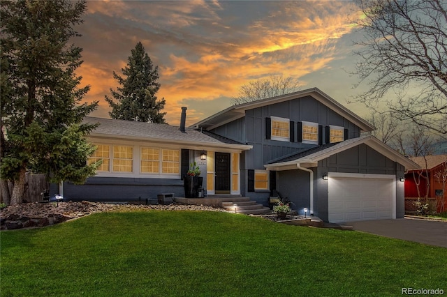 tri-level home with driveway, brick siding, board and batten siding, an attached garage, and a yard