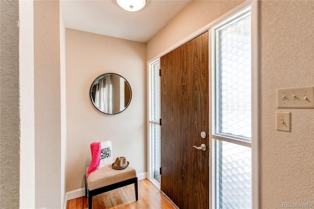 entrance foyer with baseboards, light wood-style flooring, and a textured wall