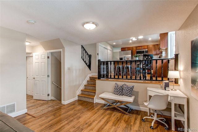 living area featuring visible vents, stairs, light wood finished floors, and baseboards