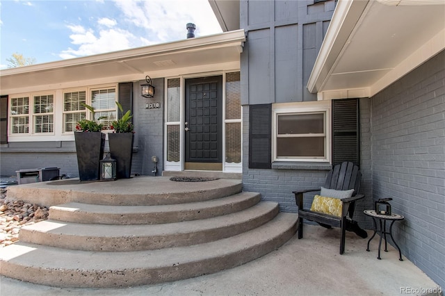 doorway to property with brick siding and board and batten siding
