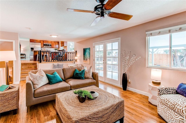 living area with a ceiling fan, baseboards, and light wood-style flooring