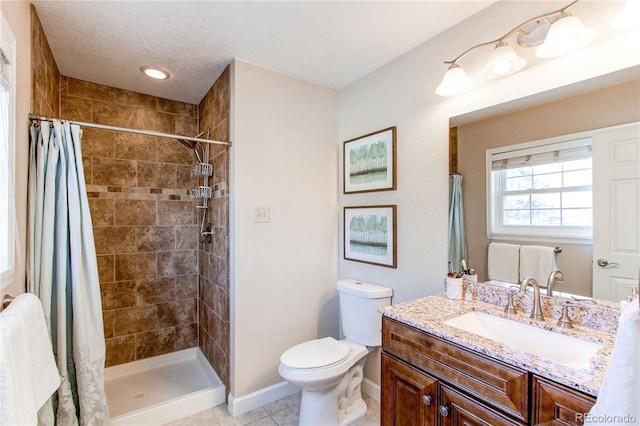 bathroom with tile patterned flooring, vanity, baseboards, toilet, and tiled shower