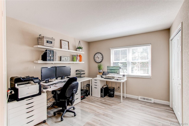 home office with baseboards, visible vents, and wood finished floors