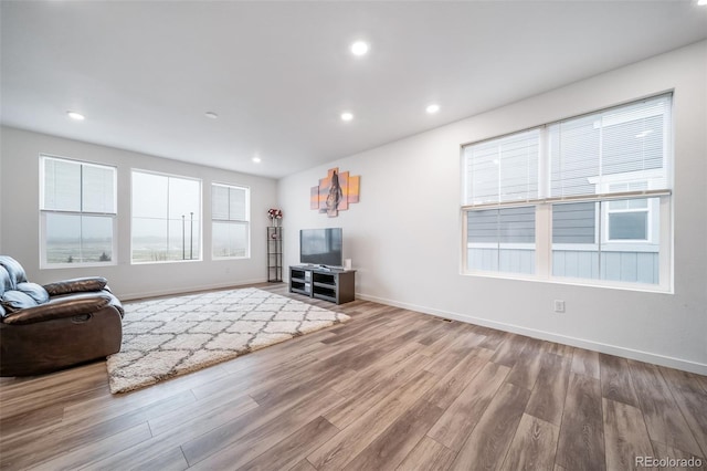 unfurnished living room featuring recessed lighting, baseboards, and wood finished floors