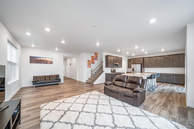 living area featuring light wood-style flooring, recessed lighting, and stairway