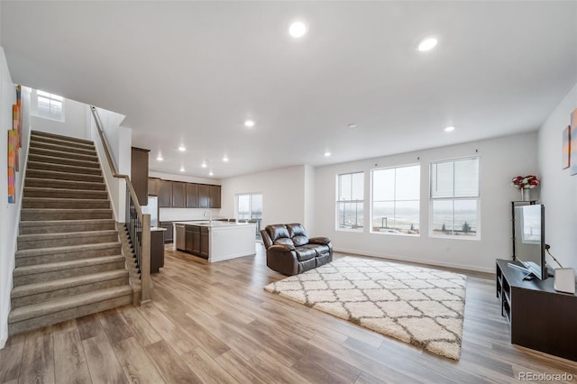 living area featuring light wood finished floors, stairway, and recessed lighting