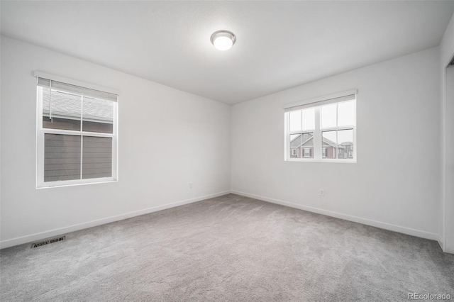 empty room with carpet, visible vents, and baseboards