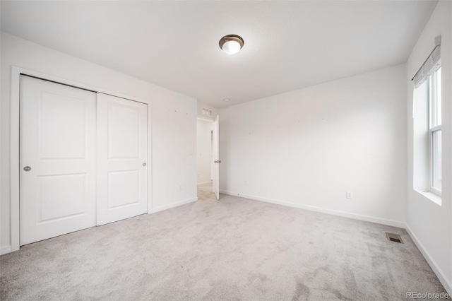 unfurnished bedroom featuring carpet floors, a closet, visible vents, and baseboards