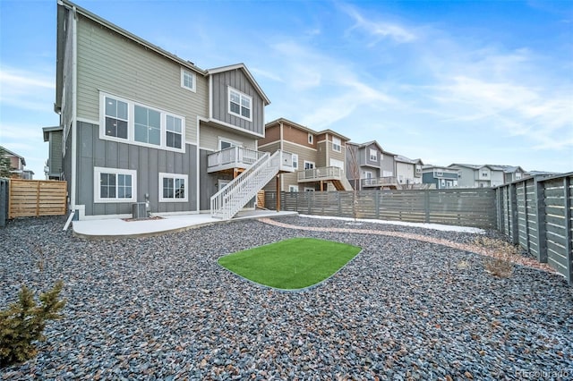 rear view of house with a patio, central AC unit, board and batten siding, a fenced backyard, and stairs