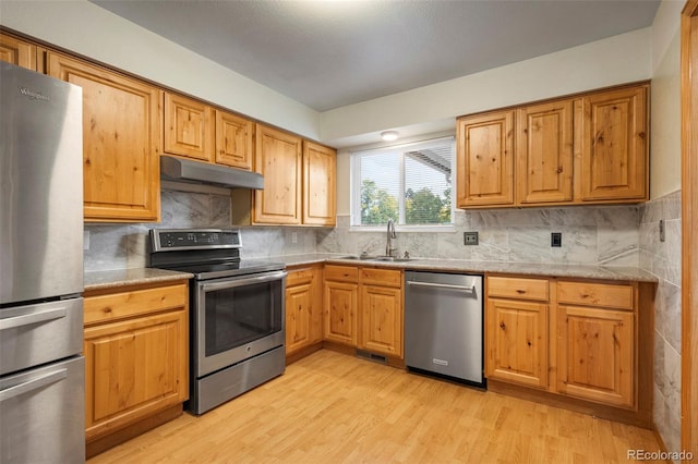 kitchen featuring sink, stainless steel appliances, light wood-type flooring, and tasteful backsplash