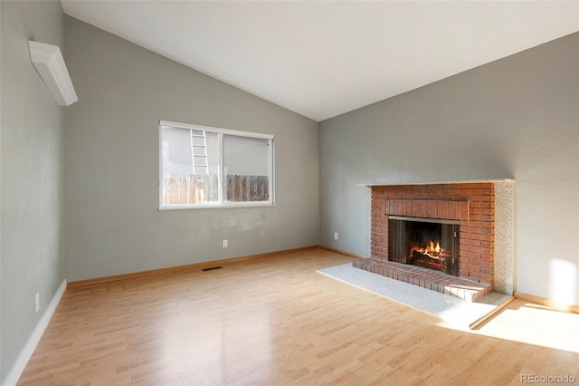 unfurnished living room with lofted ceiling, a fireplace, and light wood-type flooring