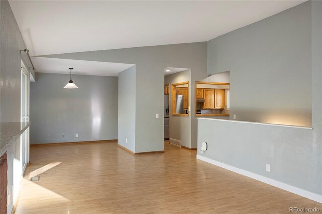 unfurnished living room featuring vaulted ceiling and light wood-type flooring