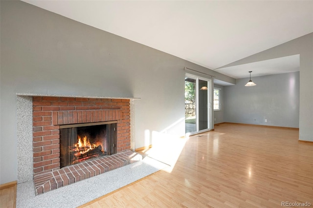 unfurnished living room featuring hardwood / wood-style flooring, vaulted ceiling, and a fireplace