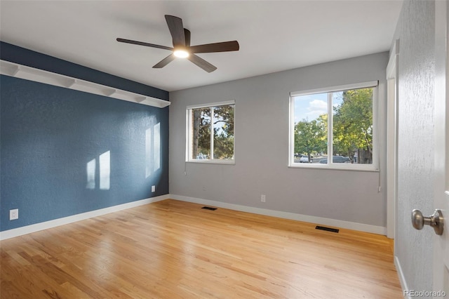 empty room with ceiling fan, wood-type flooring, and a wealth of natural light