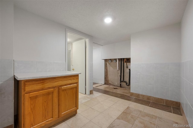 bathroom featuring vanity, tile patterned floors, a textured ceiling, and tile walls