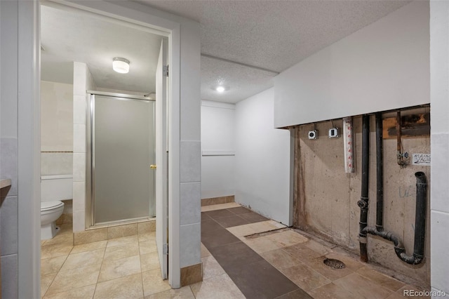 bathroom featuring tile patterned flooring, a textured ceiling, toilet, and walk in shower