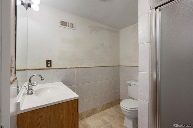 bathroom with vanity, toilet, tile walls, and tile patterned flooring