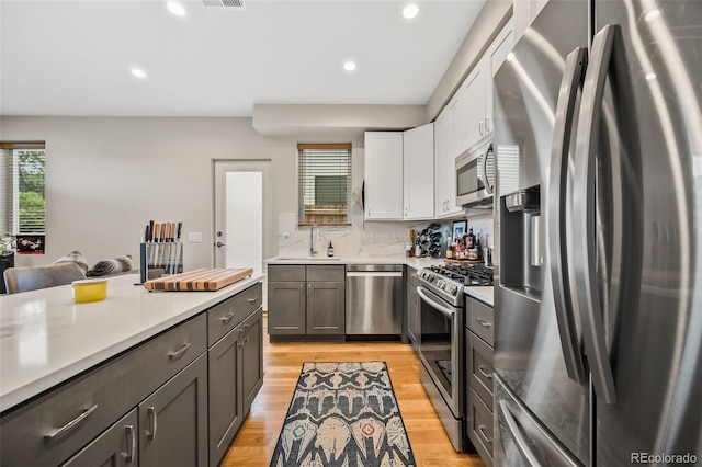 1302 N Stuart St, Denver, CO 80204 - kitchen with stainless steel appliances, light countertops, white cabinets, light wood finished floors, and recessed lighting