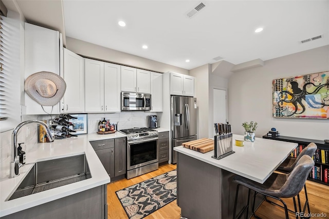 1302 N Stuart St, Denver, CO 80204 - kitchen featuring appliances with stainless steel finishes, a breakfast bar, light countertops, decorative backsplash, and a center island