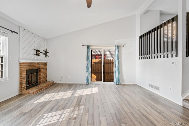 unfurnished living room with ceiling fan, lofted ceiling, a fireplace, and light hardwood / wood-style flooring