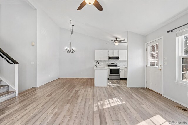 10731 W 63rd Ave Unit A, Arvada, CO 80004 - unfurnished living room featuring a ceiling fan, light wood-style floors, stairway, a chandelier, and vaulted ceiling