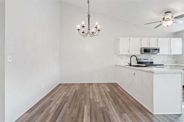 kitchen featuring appliances with stainless steel finishes, light wood-style flooring, white cabinetry, lofted ceiling, and tasteful backsplash