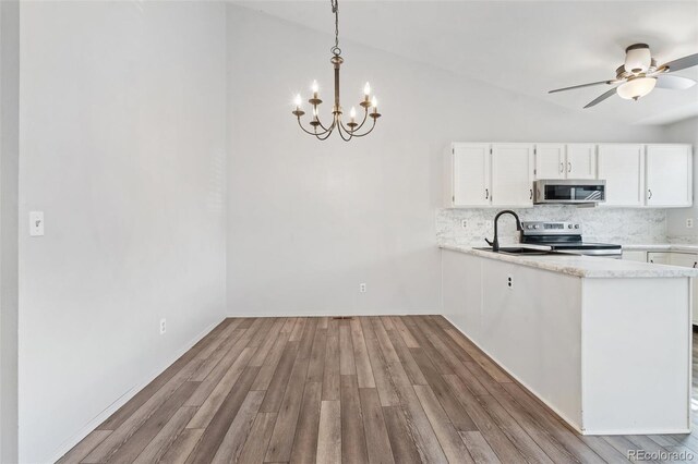 10731 W 63rd Ave Unit A, Arvada, CO 80004 - kitchen with stainless steel appliances, decorative backsplash, vaulted ceiling, white cabinetry, and a chandelier