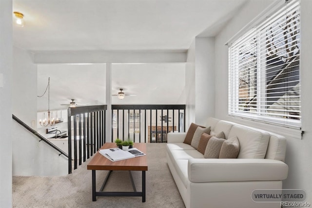 living area with carpet and ceiling fan with notable chandelier
