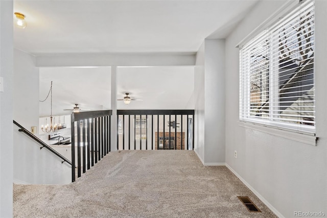 stairs featuring carpet floors, baseboards, ceiling fan with notable chandelier, and visible vents