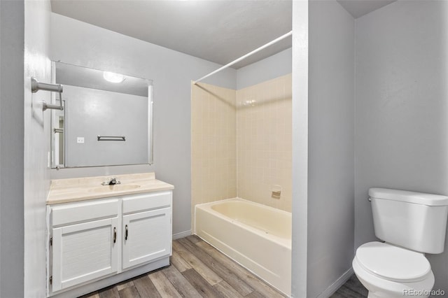 full bath featuring bathtub / shower combination, wood finished floors, vanity, baseboards, and toilet