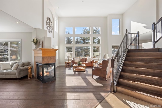 interior space with a high ceiling, a multi sided fireplace, and dark wood-type flooring