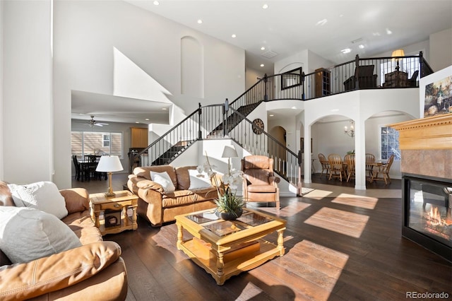 living room with a towering ceiling, dark hardwood / wood-style floors, a fireplace, and a notable chandelier