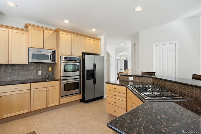 kitchen featuring light brown cabinetry, tasteful backsplash, and stainless steel appliances