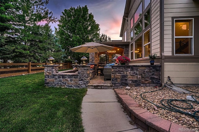 patio terrace at dusk featuring a yard