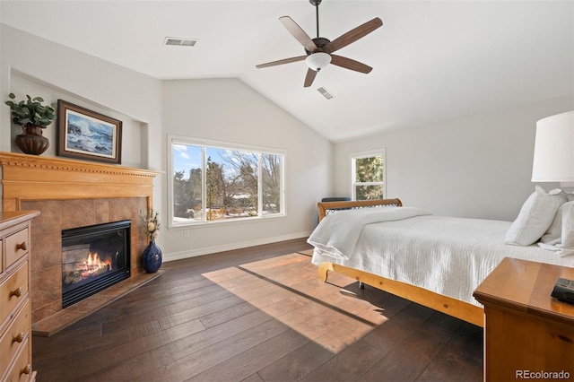 bedroom featuring a tile fireplace, dark hardwood / wood-style flooring, lofted ceiling, and ceiling fan