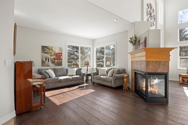 living room featuring a tiled fireplace and dark hardwood / wood-style flooring