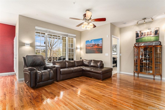 living area with baseboards, ceiling fan, and light wood finished floors