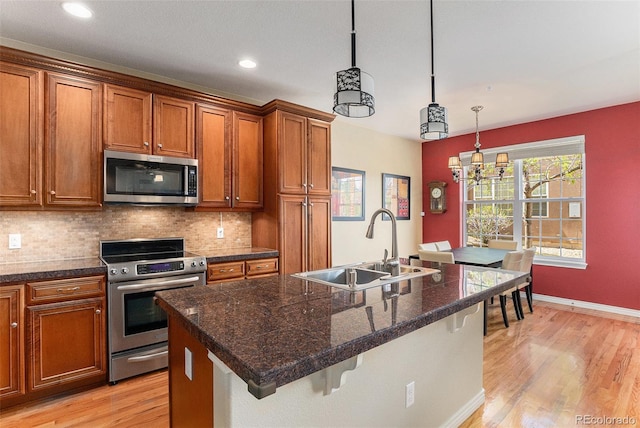 kitchen featuring brown cabinets, a sink, light wood finished floors, a breakfast bar, and stainless steel appliances