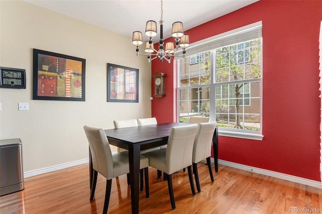 dining space with baseboards, wood finished floors, a notable chandelier, and a wealth of natural light