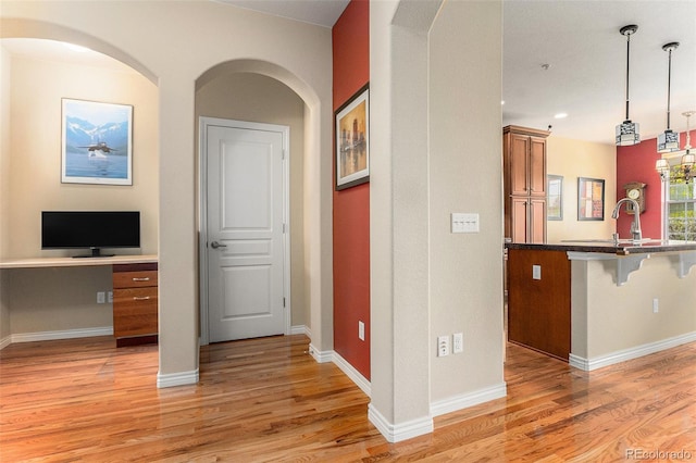 corridor with baseboards and light wood finished floors