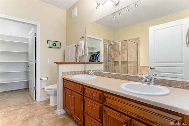full bathroom with double vanity, a walk in closet, a sink, and a stall shower