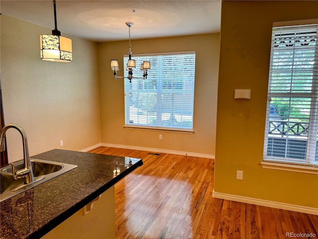 11962 W Long Cir Unit 103, Littleton, CO 80127 - kitchen featuring light wood-style flooring, dark countertops, and decorative light fixtures