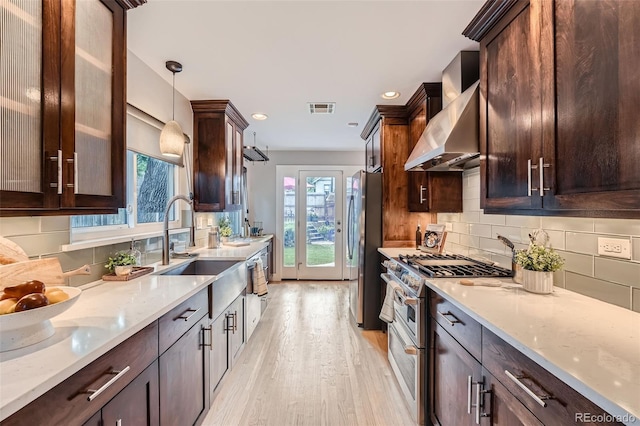 3530 E 8th Ave, Denver, CO 80206 - kitchen with appliances with stainless steel finishes, wall chimney range hood, light wood-style floors, dark brown cabinets, and light stone counters