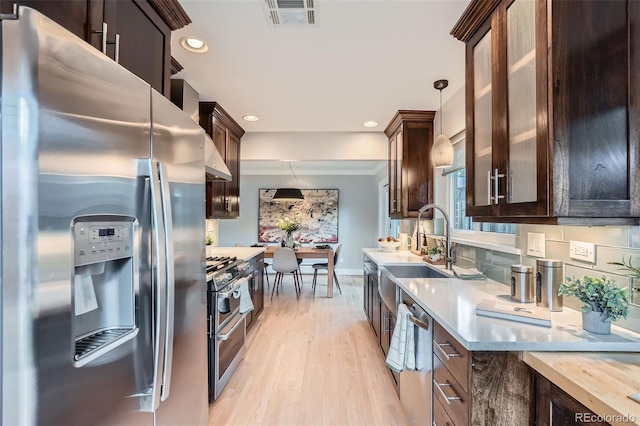 3530 E 8th Ave, Denver, CO 80206 - kitchen with stainless steel appliances, dark brown cabinetry, light wood-type flooring, decorative light fixtures, and recessed lighting