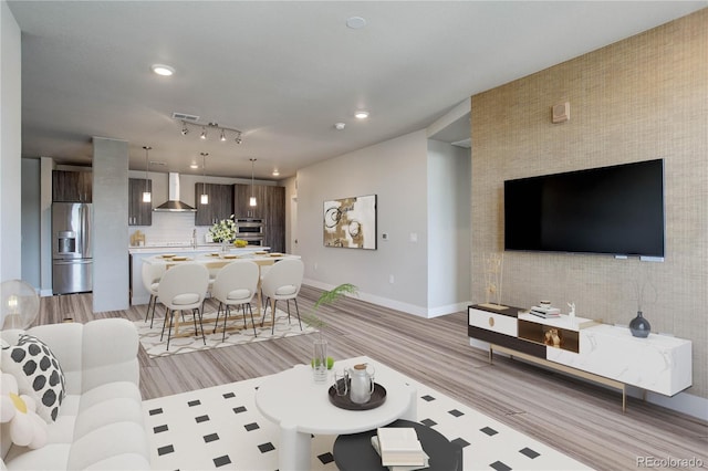 living room with rail lighting and light wood-type flooring